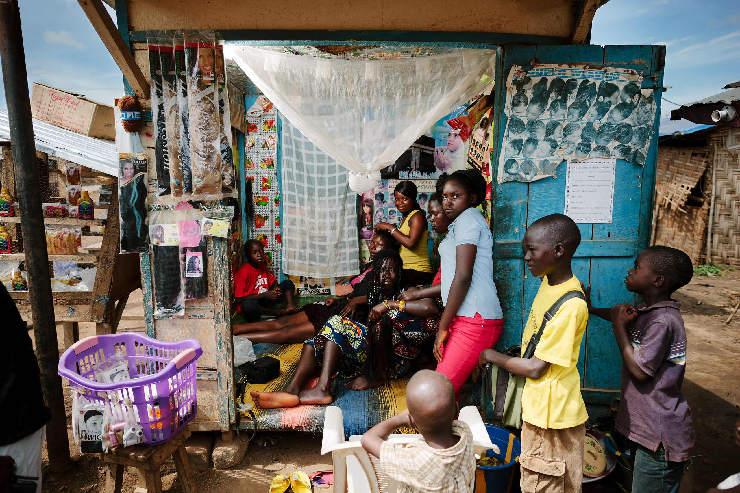 Sierra Leone hairdresser surrounded by kids, photographed in the eastern city of Kenema